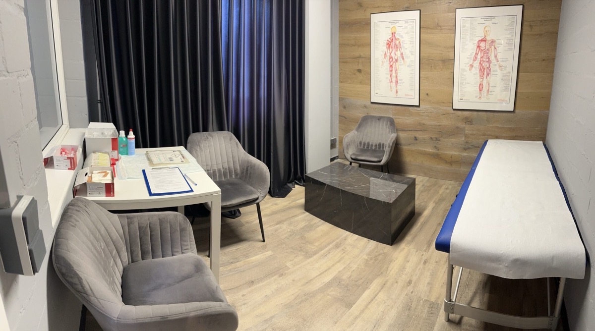 Behandlungsraum mit Liege, Sitzecke und Anatomie-Postern
