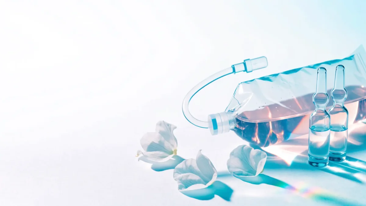 Infusionsbeutel mit Glasampullen und weißen Blüten
