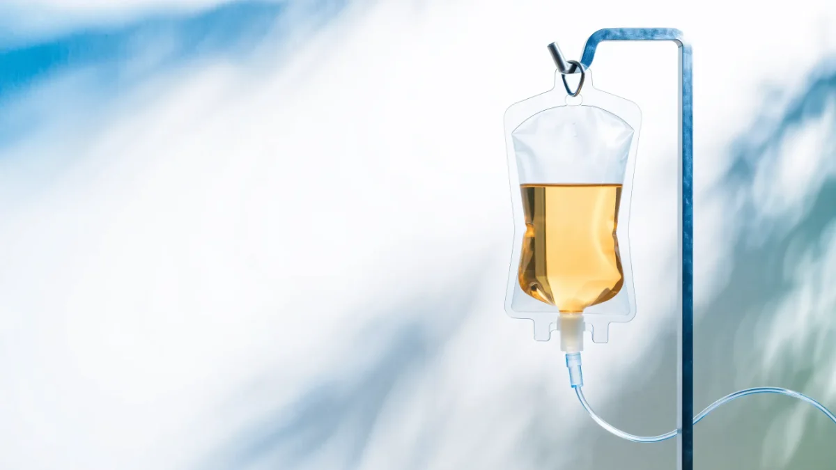 Infusionsbeutel mit goldfarbener Lösung an einem Infusionsstativ