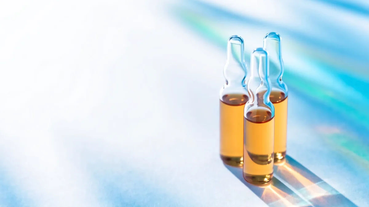 Drei Glasampullen mit bernsteinfarbener Vitaminlösung